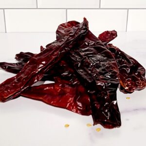 A pile of New Mexico Chiles on a marble counter.