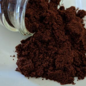 A jar of Clove Powder ~ Certified Organic on a white plate.