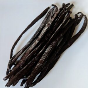 A pile of black Vanilla Beans, Bourbon on a white plate.
