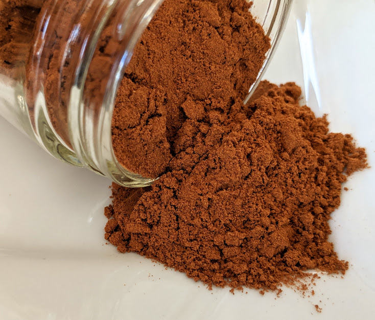 Cinnamon powder, Saigon ~ Certified Organic in a jar on a white plate.