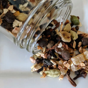 A jar full of Silk Road Mulling Spices and nuts on a white plate.