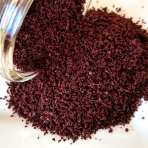 A jar of Sumac Berry Powder ~ Certified Organic on a white plate.