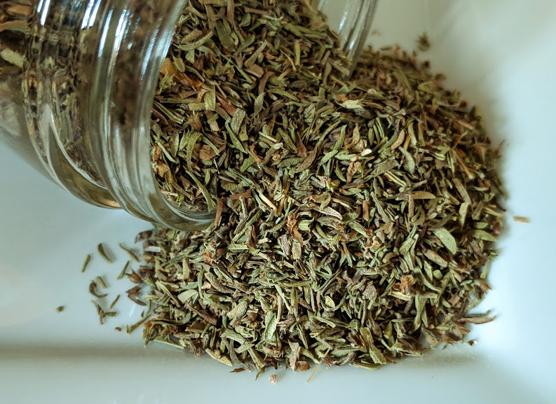 A jar of Thyme Leaf ~ Certified Organic on a white plate.