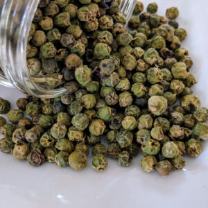 A jar of Green Peppercorns, Certified Organic on a white plate.