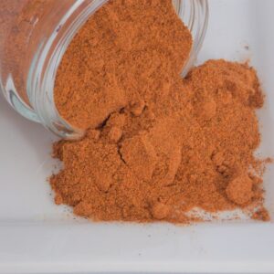 A jar of Annatto Powder ~ Certified Organic on a white plate.